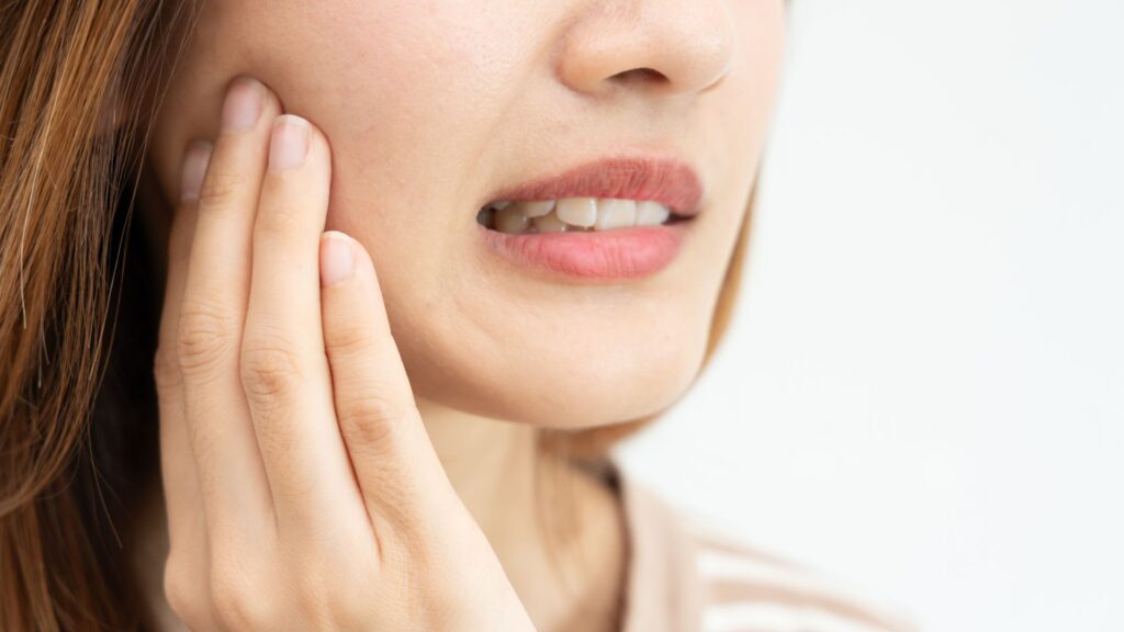 Close-up of woman feeling tooth pain when chewing on one side of her mouth