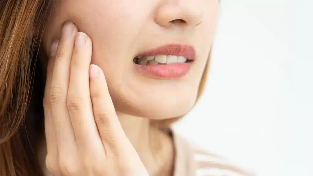 Close-up of woman feeling tooth pain when chewing on one side of her mouth
